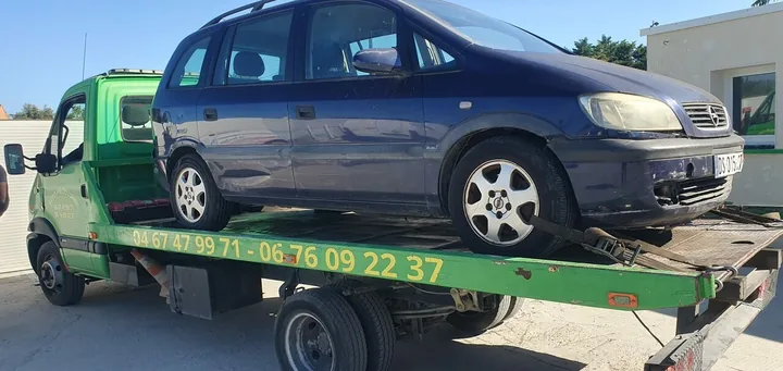 Voiture bleue vue de côté sur un camion-plateau vert.