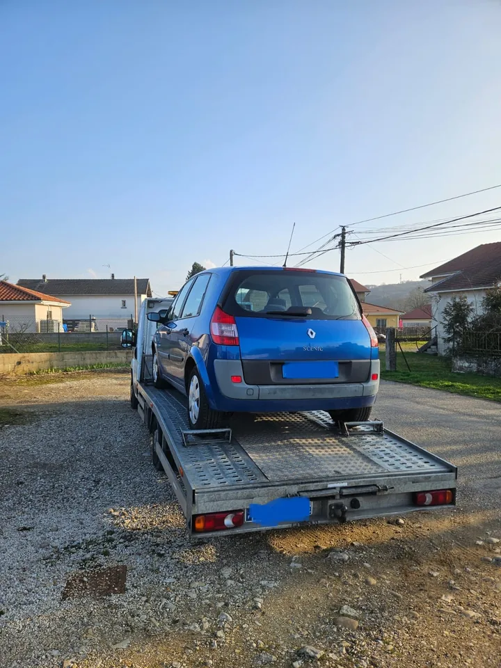 Voiture bleue sur une remorque dont les deux rampes rejoignent le sol.