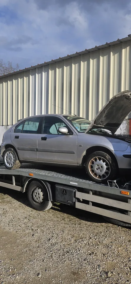 Voiture grise vue de côté sur un plateau devant un bâtiment.
