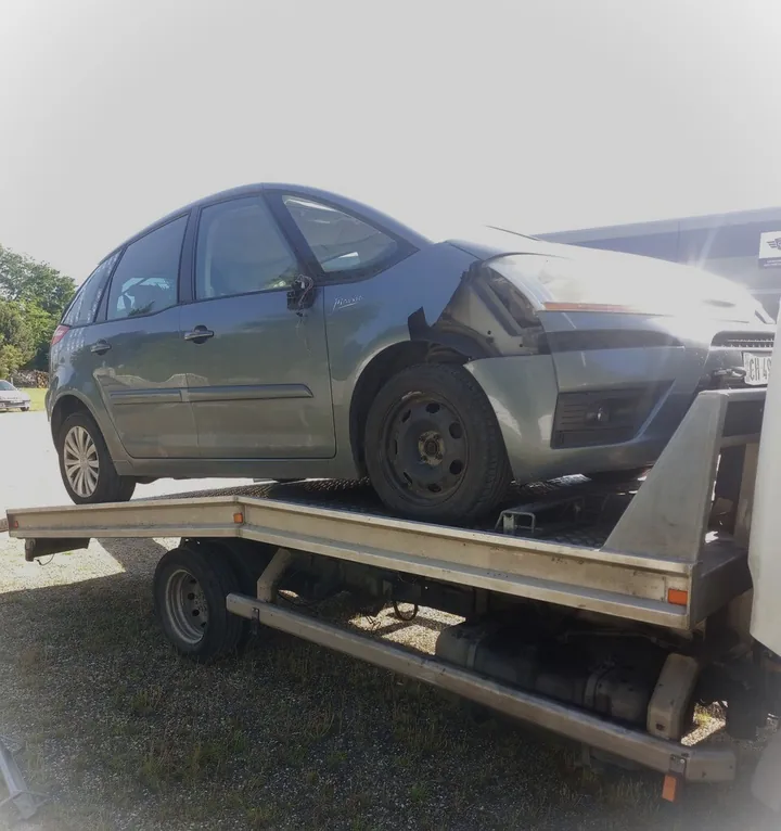 Voiture grise au pare-chocs avant abîmé installée sur un plateau.