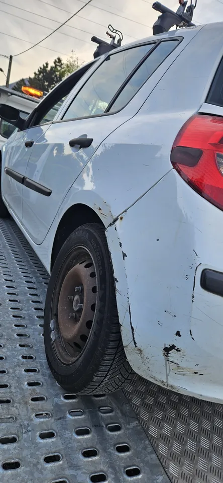 Côté d’une voiture blanche installée sur un plateau, avec la roue arrière visible.
