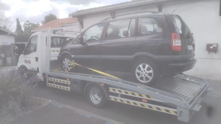 Monospace sur un camion blanc avec une sangle près d’une roue.