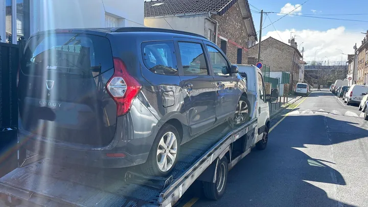 Dacia Lodgy aux portes latérales abîmées sur un camion dans une rue.