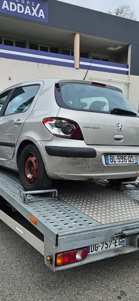 Peugeot 307 avec des marques latérales et un feu arrière abîmé sur un plateau.