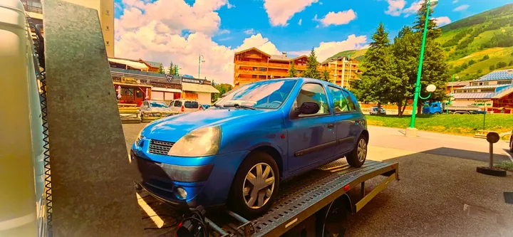 Voiture bleue installée sur un plateau dans un environnement extérieur.