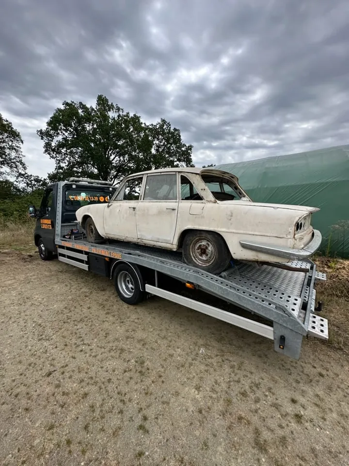 Berline ancienne avec des feux arrière absents sur une dépanneuse.