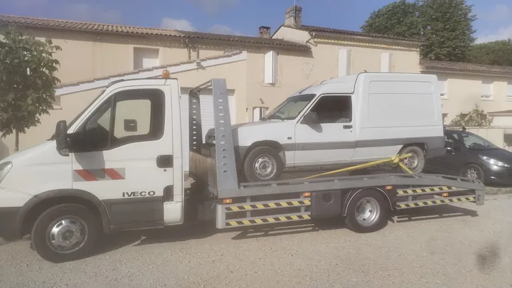 Citroën C15 chargé sur une dépanneuse avec une sangle à l’arrière.