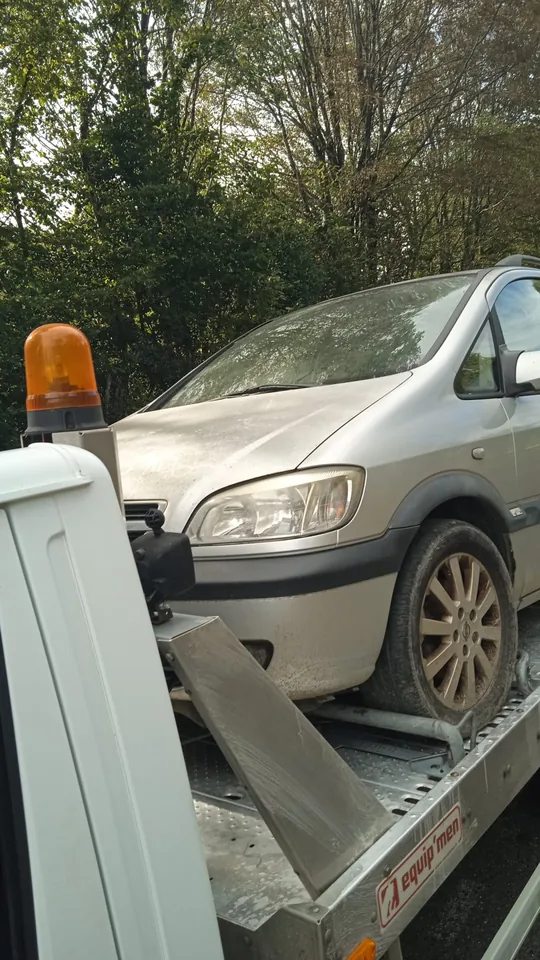 Monospace Opel sur un camion avec une cale derrière une roue avant.