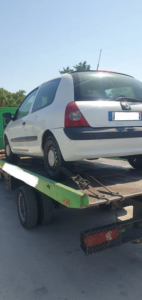Renault Clio sur un camion avec une sangle près d’une roue arrière.