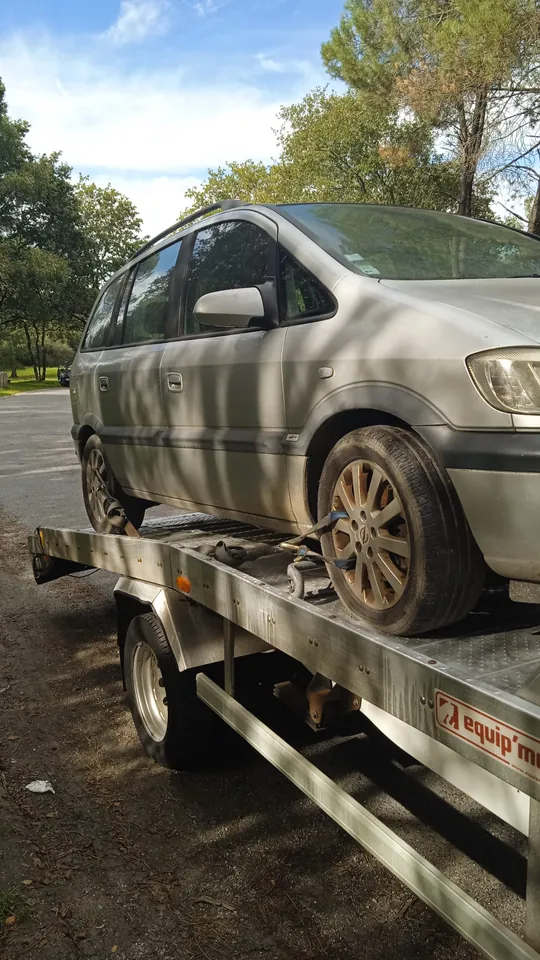 Voiture claire vue de trois quarts sur un plateau, avec sa roue avant visible.