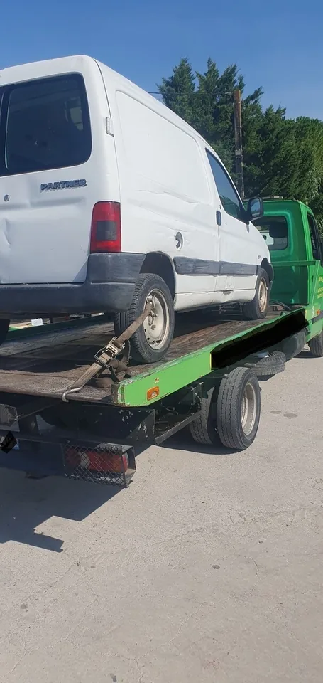Peugeot Partner sur un plateau vert avec une sangle à la roue arrière.