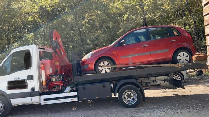 Ford Fiesta chargée derrière une grue repliée sur un camion blanc.