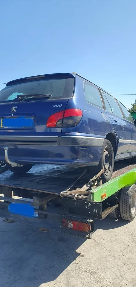 Peugeot 406 break chargé sur un plateau avec une sangle près d’une roue.