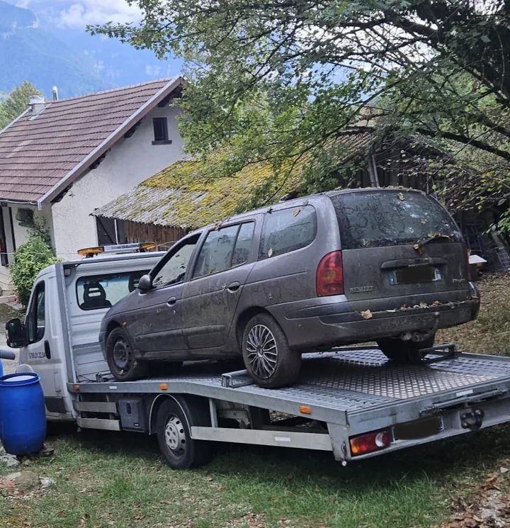 Renault Espace chargé sur une dépanneuse dans un espace résidentiel arboré.