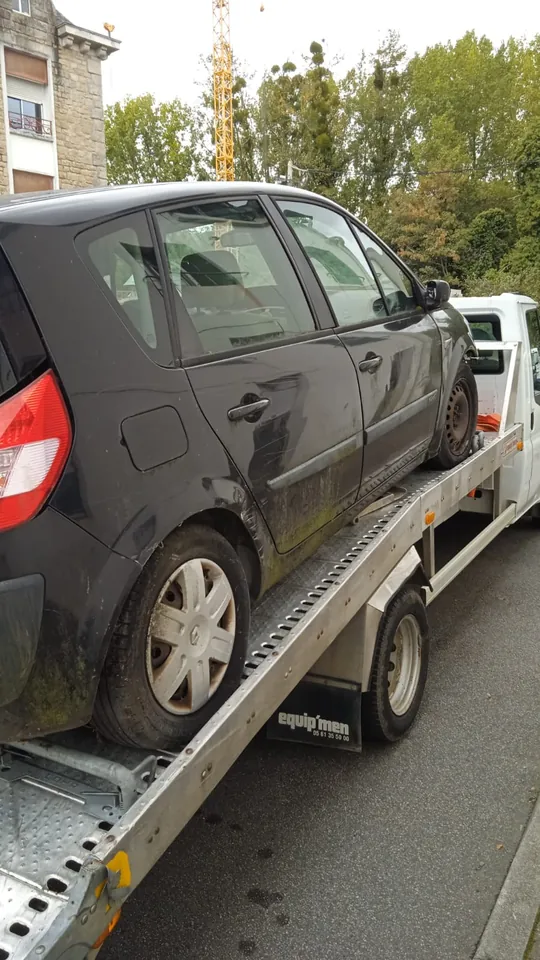 Renault Scénic aux portes latérales déformées sur un camion-plateau.