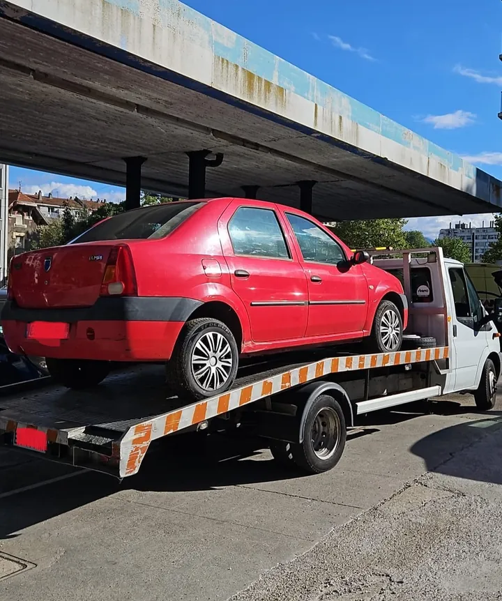 Dacia Logan chargée sur une dépanneuse près d’un ouvrage en béton.