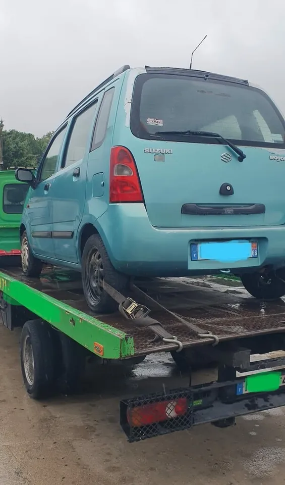 Suzuki Wagon R chargée sur un plateau avec une sangle à une roue arrière.