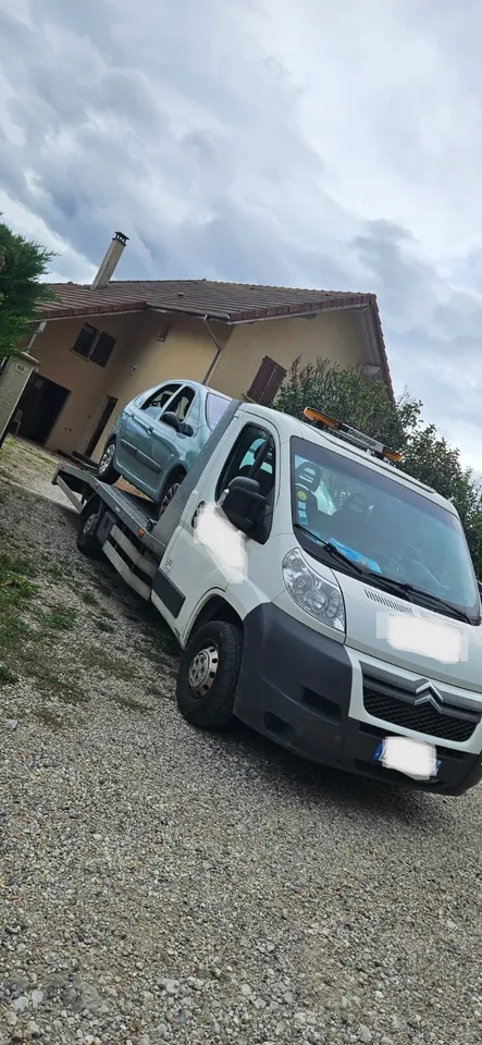Camion-plateau blanc photographié de biais dans un espace extérieur.