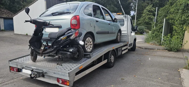 Voiture claire avec une partie arrière endommagée, installée sur un camion plateau.