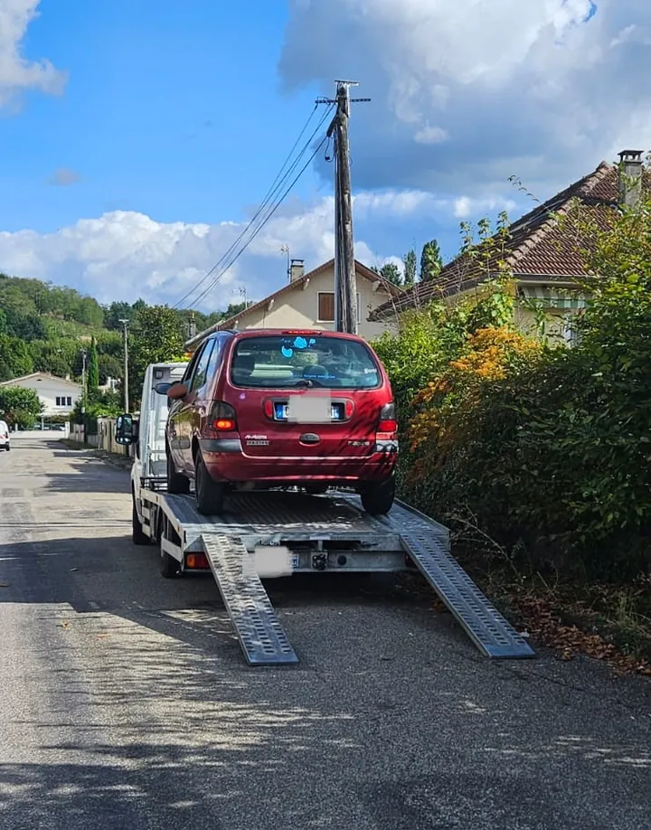 Renault Scénic sur un camion avec deux rampes abaissées sur la chaussée.
