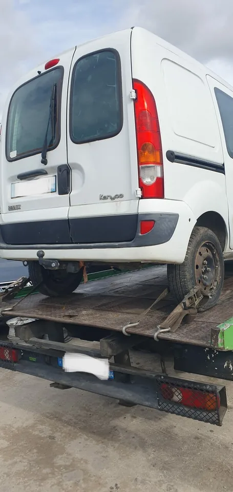 Renault Kangoo chargé sur une dépanneuse avec une sangle près d’une roue arrière.