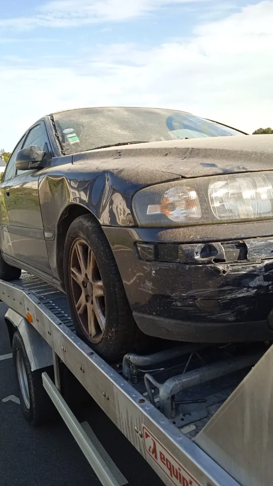 Avant abîmé d’une voiture sombre installée sur un plateau de transport.