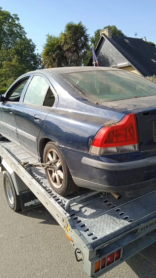 Berline sur un plateau avec une sangle près d’une roue arrière.