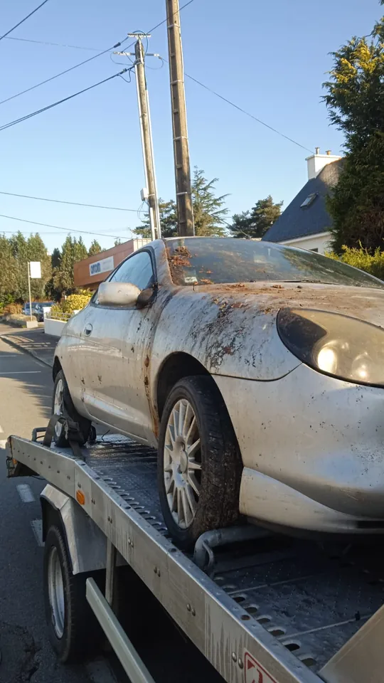 Renault Clio avec des dépôts sur la carrosserie, chargée sur un plateau.