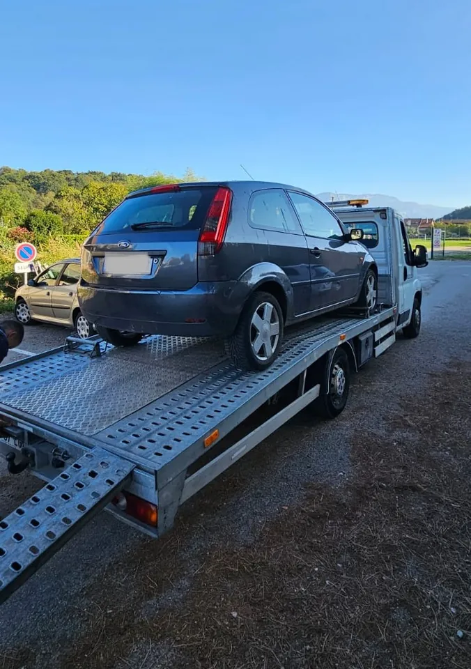 Voiture bleue vue de l’arrière sur une remorque-plateau.