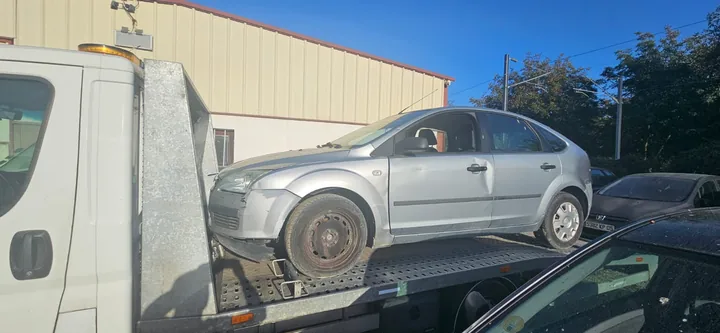 Ford Focus sur une dépanneuse devant un bâtiment industriel.