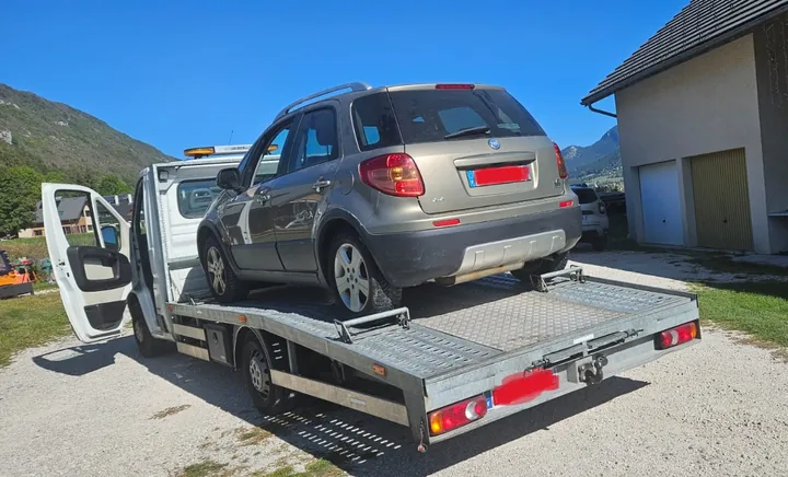Crossover Fiat chargé sur une dépanneuse devant un bâtiment.