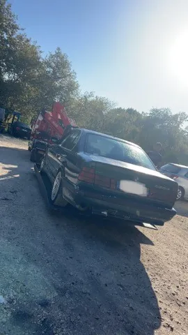 Berline sombre installée sur un camion plateau avec matériel de levage.