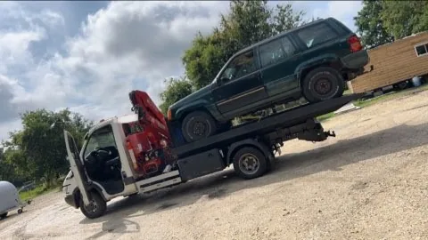 Véhicule haut de couleur sombre présenté de côté sur un camion plateau.