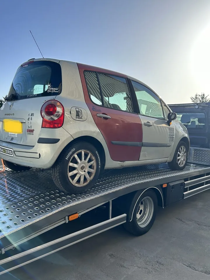Petite voiture bicolore claire et rouge installée sur un plateau métallique.