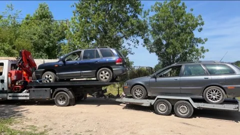 Camion portant un véhicule sombre et remorque transportant une voiture claire.