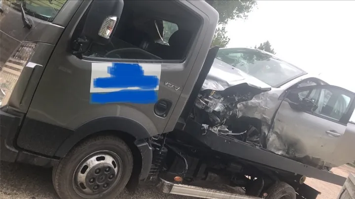 Voiture claire dont l’avant est endommagé sur le plateau d’un camion sombre.