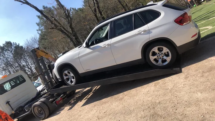 Grand véhicule blanc à carrosserie haute chargé sur une plateforme de transport.