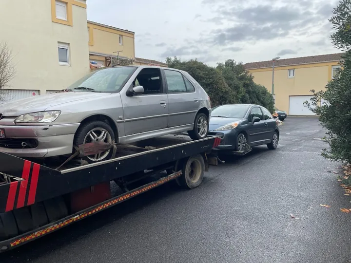 Voiture claire à cinq portes chargée sur un camion plateau dans une cour.
