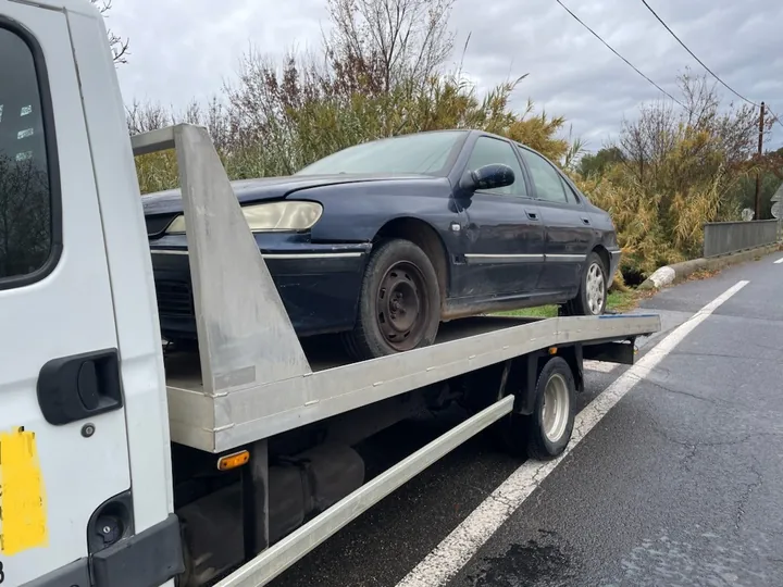 Voiture grise sur un camion blanc, avec une route visible à côté.
