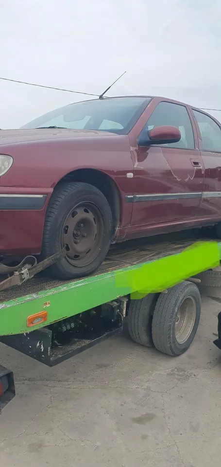 Voiture bordeaux chargée sur une plateforme de transport verte.