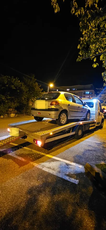 Voiture installée sur un camion plateau dans une rue éclairée de nuit.