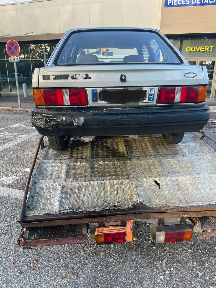 Arrière d’une berline ancienne chargée sur un plateau métallique.