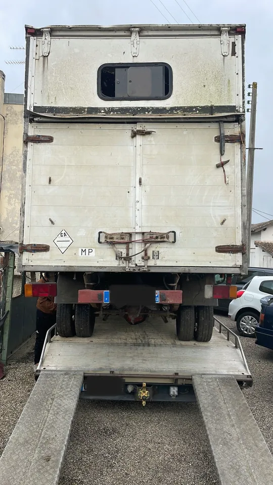 Arrière d’un utilitaire à caisse haute chargé sur une plateforme de transport.