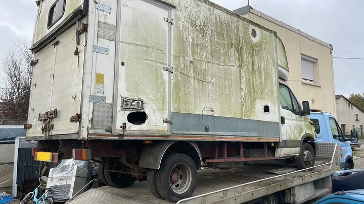 Utilitaire blanc avec une caisse haute installé sur un camion plateau.