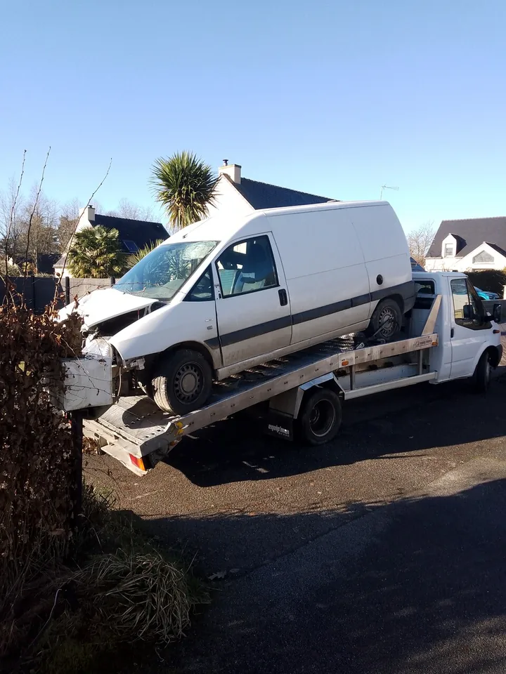 Fourgon blanc présenté de profil sur un camion plateau.