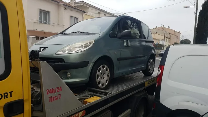 Véhicule compact gris installé sur le plateau d’un camion.