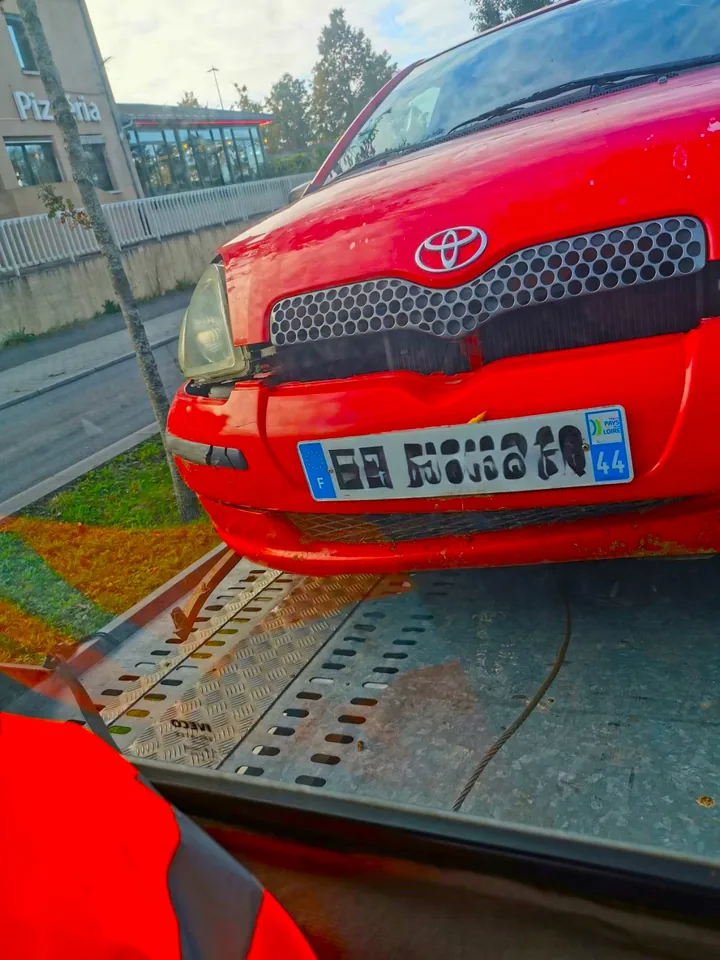 Avant d’une citadine rouge sur un plateau métallique de transport.