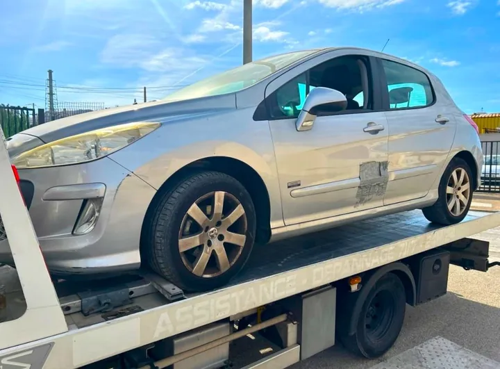 Voiture grise à carrosserie haute et portière avant marquée sur plateau.