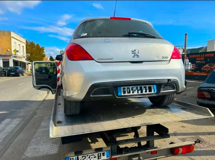 Arrière d’une voiture claire installée sur le plateau d’un camion.