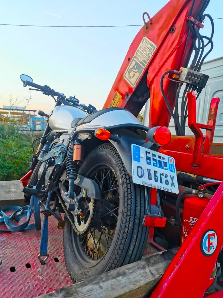 Moto sombre installée sur une plateforme près d’un bras de levage rouge.